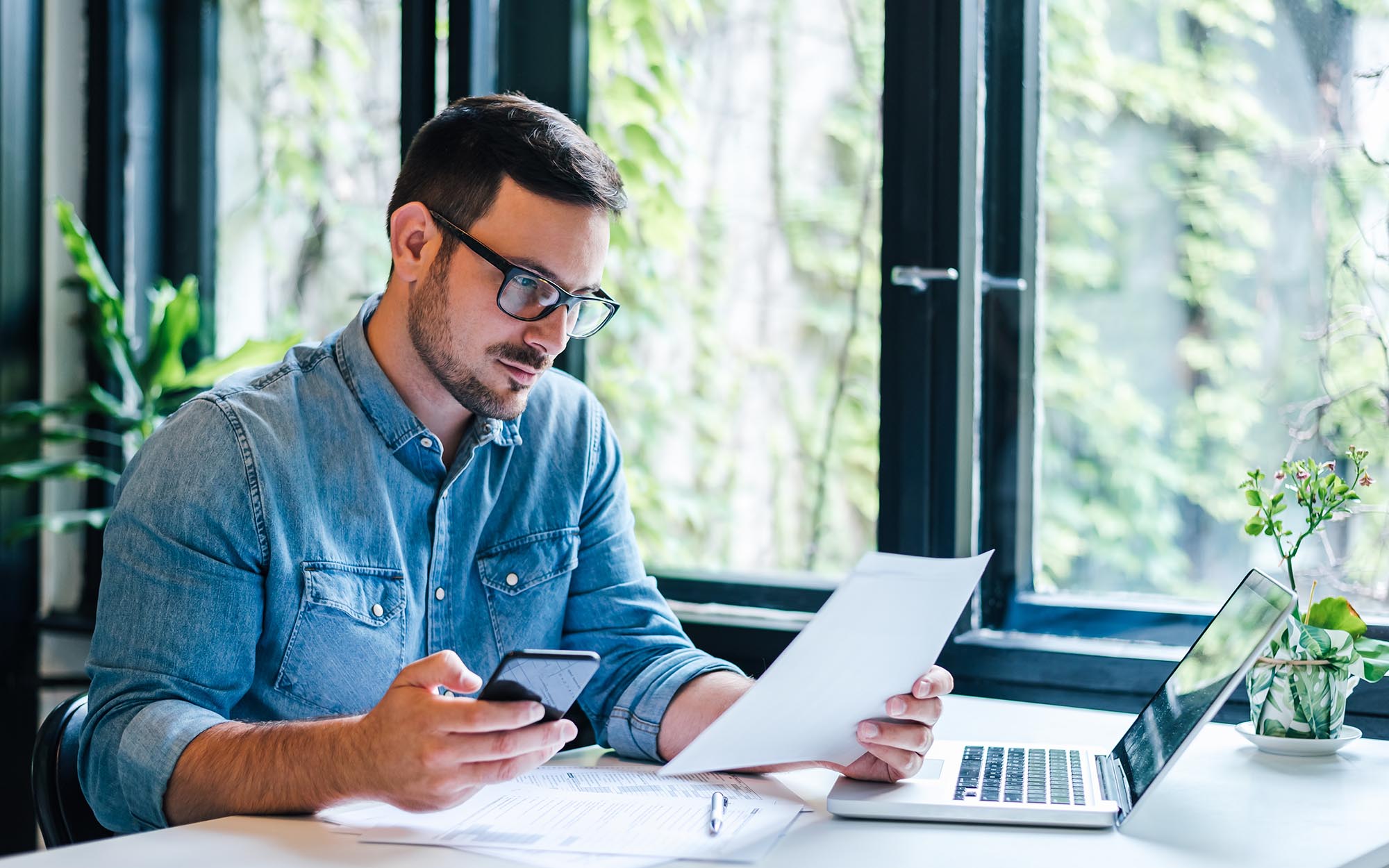 Person reviewing paperwork while using a computer for accounting services.